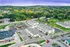 Scenic aerial view of a vibrant residential complex surrounded by lush greenery, offering modern living spaces with ample parking in a peaceful neighborhood.