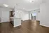 Elegant open-concept kitchen and living room with sleek wooden flooring and natural light from expansive windows.