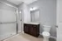 Modern bathroom featuring a sleek glass shower, elegant vanity with dark wood cabinets, and a stylish toilet, complemented by soft gray walls and bright lighting.