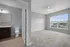 Bright bedroom with plush carpet and large windows, adjacent to a modern bathroom with elegant cabinetry.