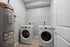 Modern laundry room with stacked washing machine, dryer, and a sleek gray water heater.