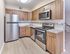 Upgraded kitchen with stainless steel appliances, wood-style cabinetry, and modern backsplash at Maple Grand Apartments in Maple Shade, New Jersey.
