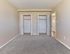 Spacious bedroom with soft carpet flooring and two large closets at Village Square Apartments.