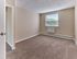 Carpeted bedroom with natural light and neutral walls at Audubon Arms Apartments.