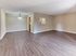 Open-concept living and dining area in the Redwood 1 2 bedroom apartment at The Villager at Barton Run in Marlton NJ featuring wood-style flooring, neutral walls, and pass-through kitchen window.