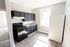 beautiful kitchen with large window, wood floor, fridge and stove, and black cabinets