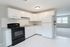 open kitchen with lots of cabinets facing large carpeted room