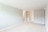 large carpeted front room facing hallway and kitchen