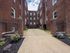 courtyard surrounded by tall brick building, concrete walkway, landscaped flower beds