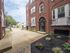 entrance to folcroft apartment building, colorful flowers in mulch bed, glass door leading into brick building with white windows, concrete walkway