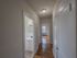 view down apartment hallway passing closet and bright bathroom, leading into bedroom
