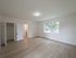 large bedroom with lots of windows, hardwood floor, overhead light, radiator, facing closet and hallway