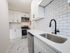 renovated kitchen with wooden cabinets and white fridge and oven/stove, apartment kitchen, black sink faucet, lots of cabinets, dishwasher, granite counters, white tile backsplash