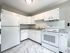 renovated kitchen, refrigerator, range with hood, stone counters, lots of cabinets, tile floor, overhead light