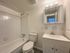 Modern bathroom with sleek white tiles, stylish vanity, and polished fixtures.