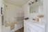 Elegant bathroom with modern fixtures, featuring a bathtub with a striped curtain, sleek white vanity, and stylish decor accents.
