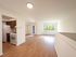 Bright open-concept living area with natural light, featuring a cozy kitchen with wooden cabinets and modern appliances, perfect for contemporary living.