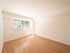 Bright and airy room with large window, showcasing modern hardwood floors and abundant natural light.