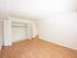 Bright and spacious bedroom featuring elegant hardwood flooring, ample closet space, and fresh white walls, ready for personalization.
