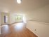Bright and inviting living room with large window and natural wood flooring, offering a serene view.