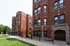 Red brick 3 story building with stone accents and green grass