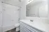 Renovated bathroom with luxury vinyl wood flooring and white cabinetry.