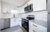 Fully renovated kitchen with stainless steel appliances, granite countertops, matte black finishes, and large window above the sink allowing for natural light to enter the kitchen and living room space.