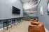 Sports Simulator game room featuring golf-inspired decor, a flat screen television with barstool seating and large leather chairs, a kitchen with small fridge and sink.
