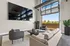 Open-air shared lounge and co-working space with multiple televisions, a large seating area, and potted plants.