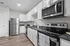 Modern kitchen with stainless steel appliances, granite countertops, soft-close cabinetry, and overhead lighting.