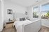 A bedroom featuring plush carpeting and warm overhead lighting. The room includes a comfortable bed, stylish furnishings, and large windows allowing natural light to fill the space.