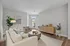 Open-layout living room with luxury vinyl wood flooring, ample space for seating, featuring comfortable furniture, and large windows that let in natural light.