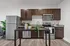 A modern kitchen featuring stainless steel appliances, including a refrigerator, oven, and dishwasher. The kitchen also showcases soft-close cabinetry, granite countertops, and overhead lighting.
