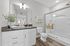 A bathroom with elevated finishes, including a vanity with modern fixtures, a walk-in glass shower, and granite countertops.