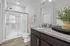 A bathroom with elevated finishes, including a vanity with modern fixtures, a walk-in glass shower, and granite countertops.