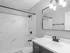 Elegant bathroom with modern fixtures, featuring a sleek vanity, large mirror, and marble-patterned walls.