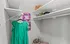 Elegant closet featuring neatly organized shelves, a vibrant green dress hanging, and tasteful decor with floral art.