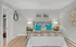 Elegant bedroom featuring a plush bed with teal pillows, soft lighting, and modern wall art, emphasizing comfort and style.