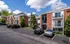 Somerset Apartments Exterior, Brick apartment buildings with balconies and parking spaces, surrounded by greenery under a bright blue sky.