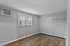Spacious and bright empty room with wooden flooring, featuring a large window and built-in air conditioning.