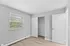 Inviting bedroom with natural light, featuring a window, closet, and stylish wood flooring.