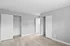 Bright and airy bedroom with light wooden floors and minimalist gray walls featuring dual closets.