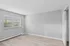 Bright and spacious empty room with large window and soft wooden flooring.