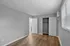 Bright bedroom with sleek wooden flooring, large window, and open closet space.