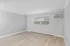 Open room with light wood flooring, large window, and wall air conditioning unit.