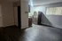 Bright kitchen area with modern stainless steel refrigerator and expansive open living area, featuring sleek flooring.
