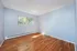 Inviting empty room with large window and elegant wooden flooring, bathed in natural light.