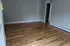 Empty room with beautiful hardwood floors, neutral walls, and ample natural light.