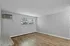 Modern living room with large window, light gray walls, wood flooring, and air conditioner.