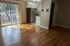 Bright living area with hardwood floors and a modern kitchen, featuring large sliding glass doors opening to a balcony.